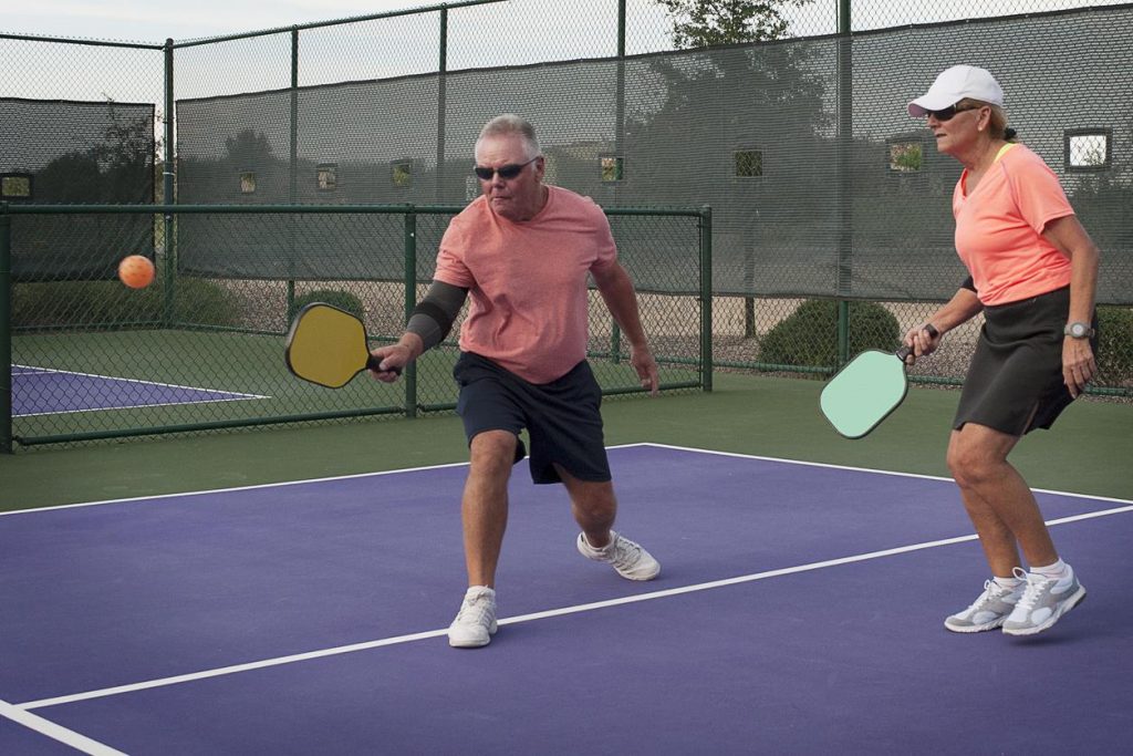 Seniors learn how to play pickleball on indoor court