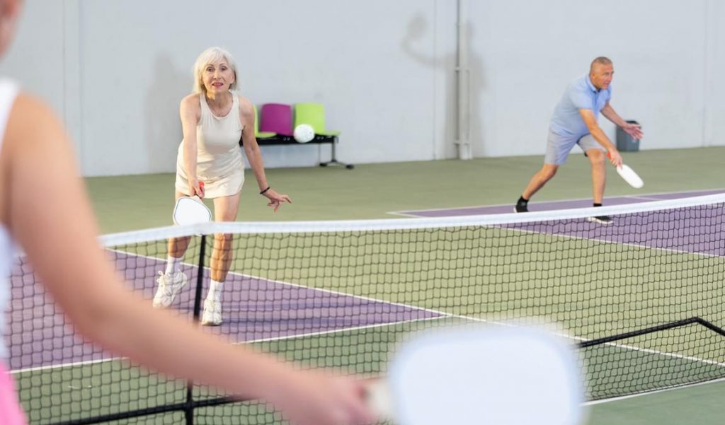 Mature couple plays pickleball on court outside